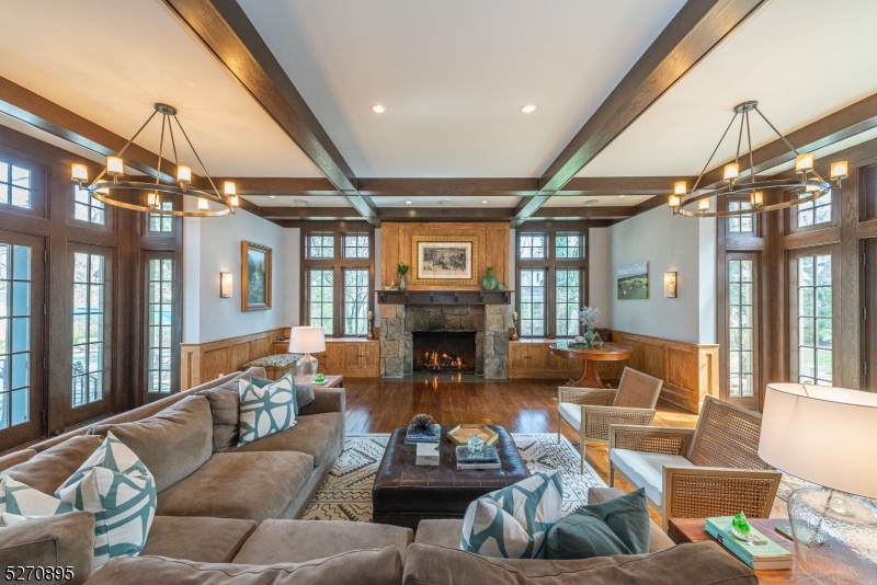The heart of the home....to the right of the kitchen dining area is the huge family room  with a stone mantled gas fireplace, beamed ceiling, wide-plank floors, wood paneling. Fenced pool outside doors on left. Courtyard outside doors on right.