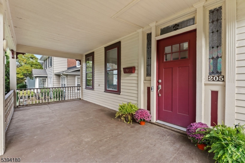 Front View Large Front Porch. Front door flanked by beautiful stained-glass windows and transom
