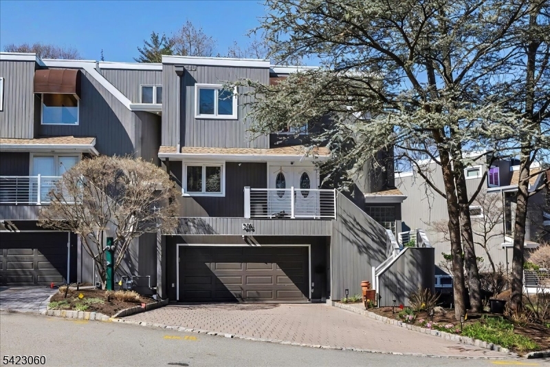 Front exterior of townhouse with modern siding and attached garage. Stairway leading to main entrance.