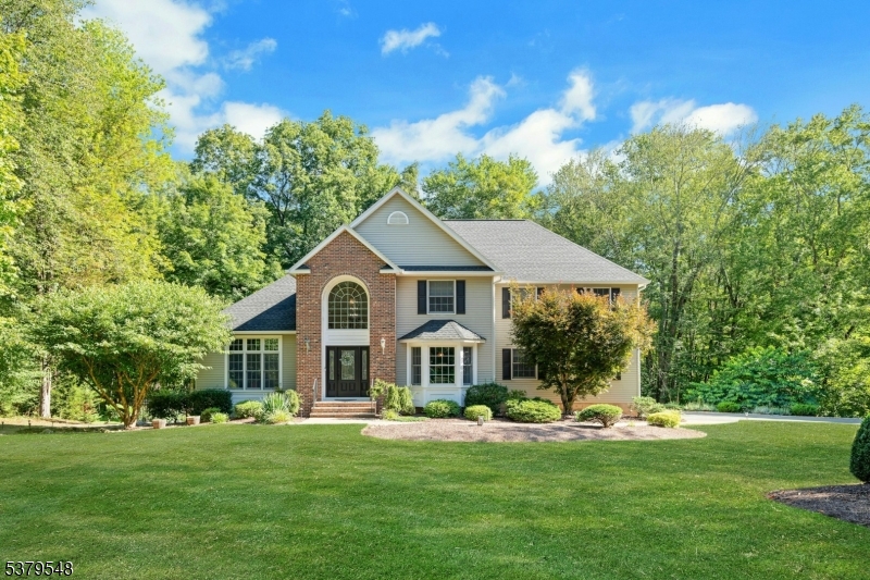 Stately brick-front colonial nestled among the trees, offering timeless charm and a serene-wooded setting.