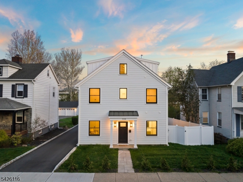 The striking facade of this Tim Klesse-designed front unit shines at twilight. Expertly placed exterior lighting highlights the superior craftsmanship and lush landscaping of this Millburn newcomer.