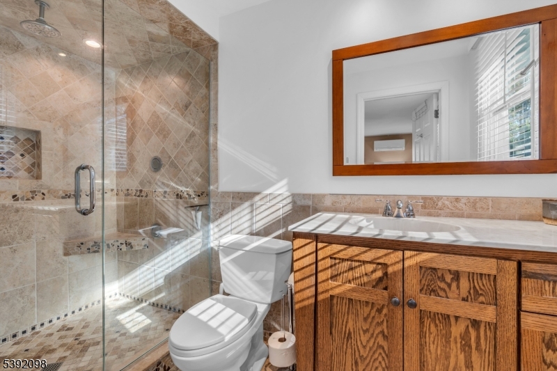 Primary full bath Double walk-in shower, tiled surround with glass door entry. Oak double vanity, tiled flooring.