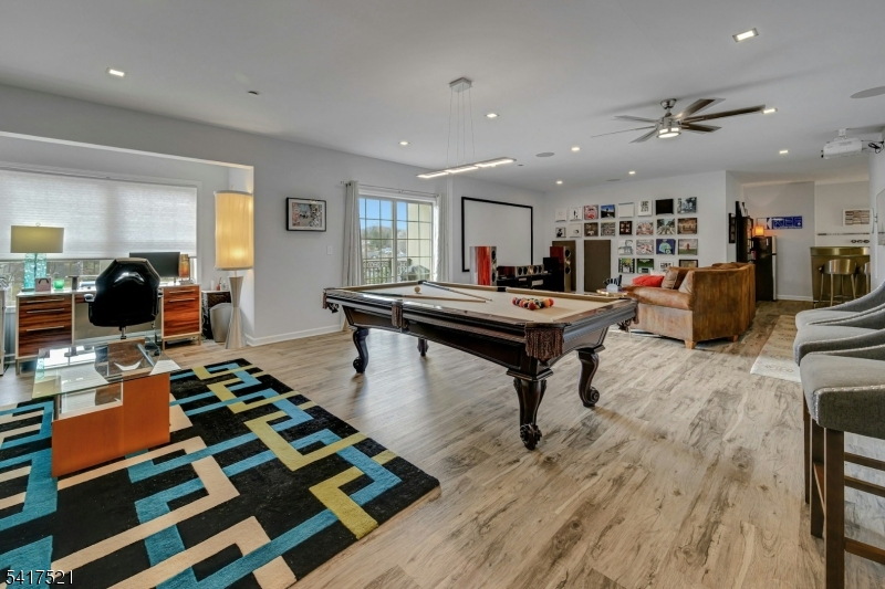 Enjoy a dedicated game area with pool table, comfortable lounge seating, and a stylish home office nook, all enhanced by large windows that bring in abundant natural light.