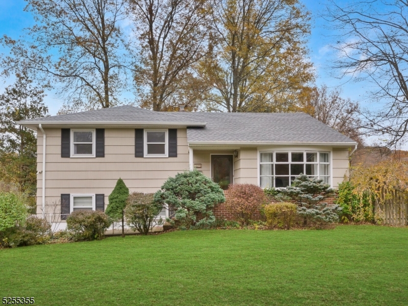 Welcome to this charming split-level home featuring a sprawling, manicured front lawn, mature landscaping, and a classic exterior with attractive shutter accents.