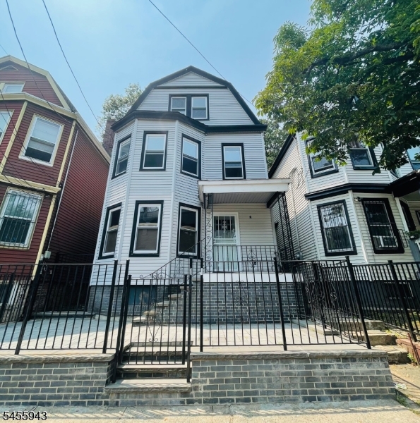 823 S 14th st Home features classic architectural character, a welcoming covered front porch, bay-style windows, updated siding, and a fenced front entry with a spacious raised patio area.