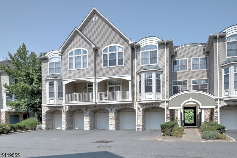 Front View Elegant multi-level townhome with a private balcony, arched windows, and direct-entry garage in a beautifully maintained community