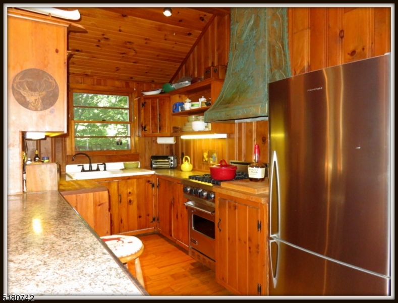 custom copper etched hood over Viking Gas stove, Fisher Paykel Stainless Steel Refrigerator, deep cast ireon sink window overlooks the lake