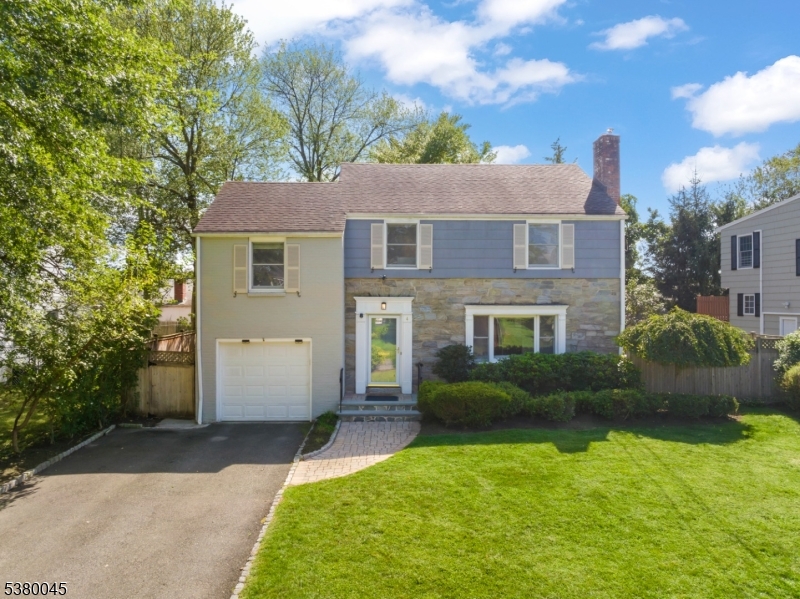 Charming Colonial curb appeal with manicured lawn, attached garage, and welcoming entry.