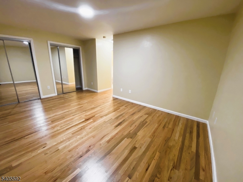 Generously sized primary bedroom featuring hardwood floors, neutral paint, and excellent closet storage with mirrored sliding doors. The open footprint offers room for a king bed and extra furniture, creating a comfortable, easy-to-furnish retreat.