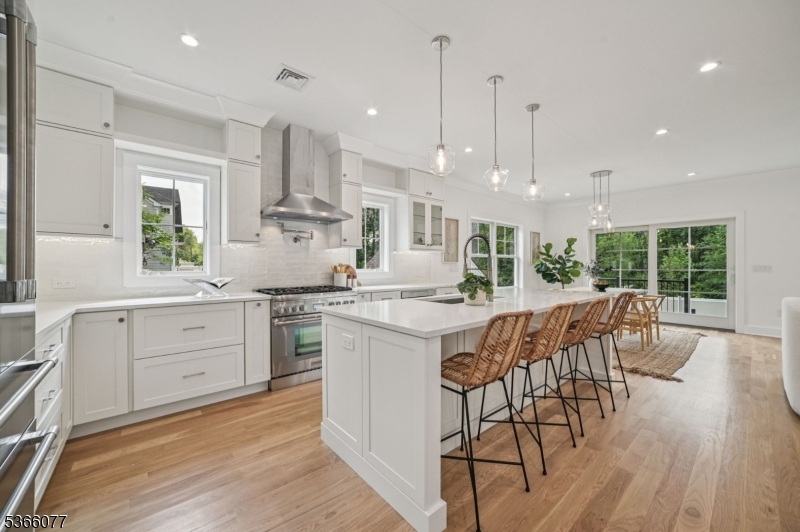 Open kitchen with custom cabinetry, Thermador appliances, quartz countertops & island seating