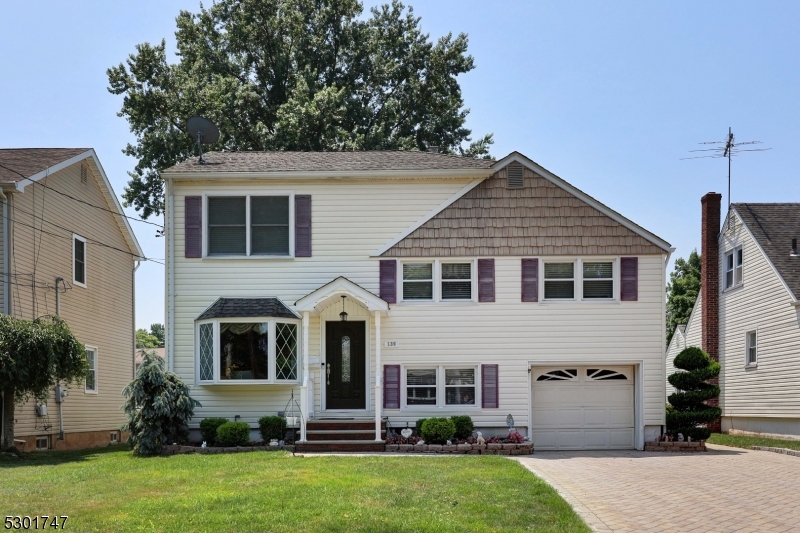 Vinyl siding, double wide paver driveway with walkway leading to the backyard