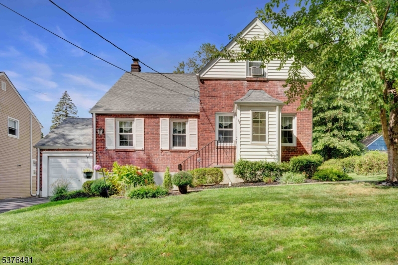 Inviting curb appeal with brick and siding, lush lawn, and mature landscaping.