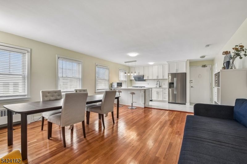 Living room / Dining room Bright, open-concept space boasting gleaming hardwood floors, large windows, and a seamless flow into the kitchen.