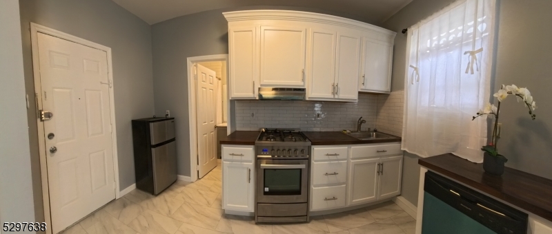 Newly renovated kitchen with porcelain flooring and subway tile backsplash.