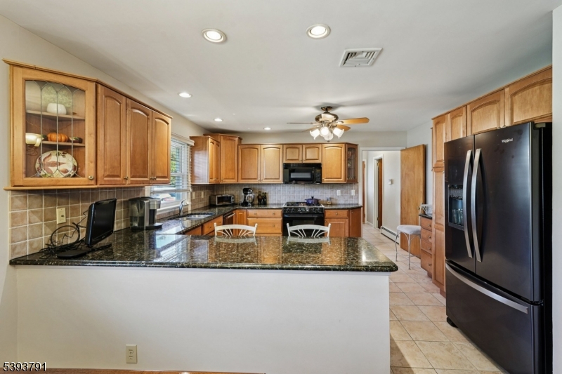 Kitchen The eat in kitchen features custom cabinetry, granite countertops, black stainless steel appliances and bar stool seating.