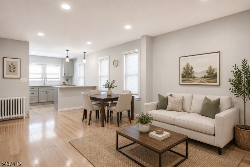 Virtually staged to showcase the bright, open-concept living and dining area, featuring hardwood floors, recessed lighting, abundant natural light, and a seamless flow into the beautifully updated kitchen with breakfast bar and modern finishes.