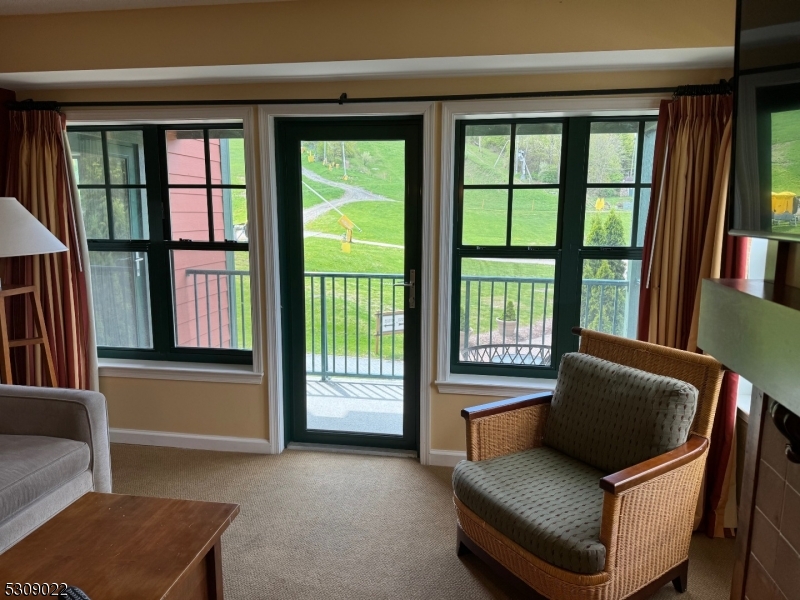 Living room area with entrance to private deck with mountain views.