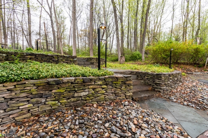 Additional natural stone wall right side of home with walkway all the way around