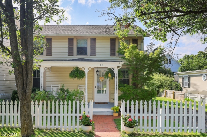 This home offers the charm of a white picket fence, covered porch with rocking chairs and modern updates inside the home.