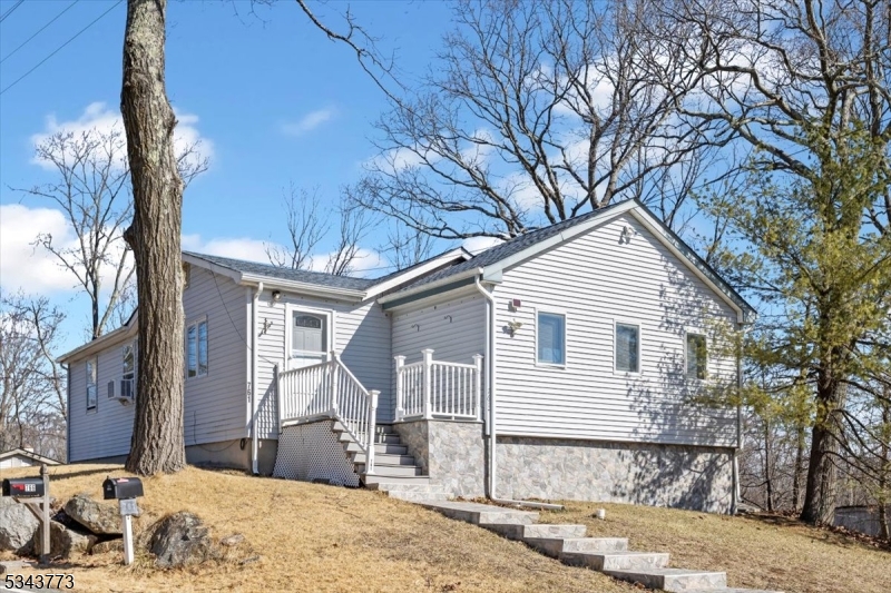 Front view of home with steps leading to Trex deck. Newer viinyl siding and roof.